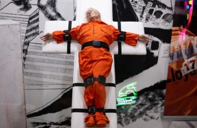 Γλυπτό από ρητίνη τιτλοφορείται «Άγιος ή Αμαρτωλός» και εικονίζει τον Αμερικανό πρόεδρο ντυμένο με φόρμα κρατουμένου, δεμένο σε φορείο σε σχήμα σταυρού