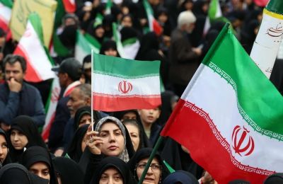  Ιρανοί, μεταξύ αυτών και γυναίκες, κρατούν σημαίες του Ιράν και στέκονται στο πλευρό του καθεστώτος.
